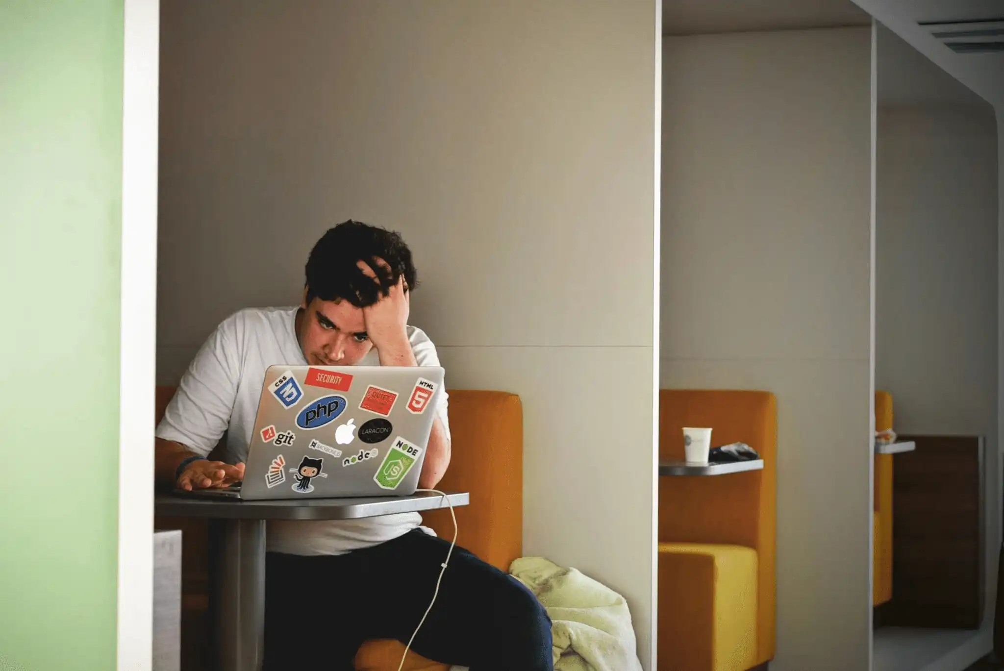 One person infront of a laptop, stressed, buried under competing demands.
