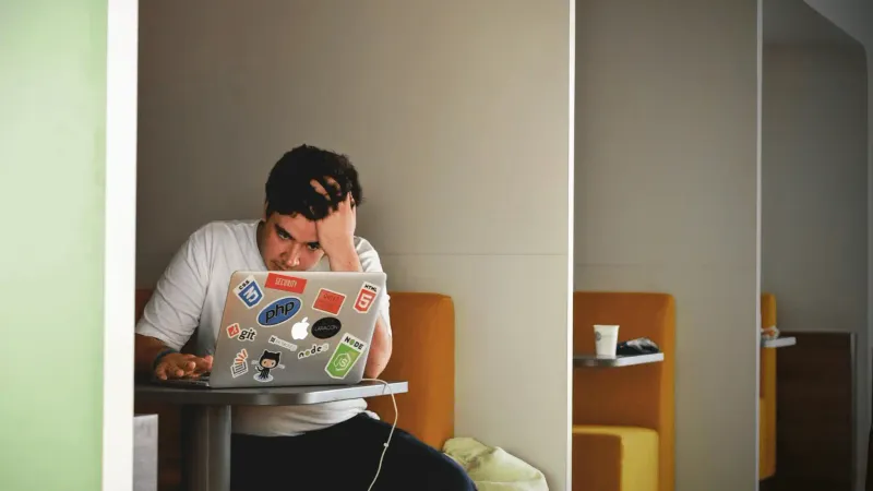 One person infront of a laptop, stressed, buried under competing demands.